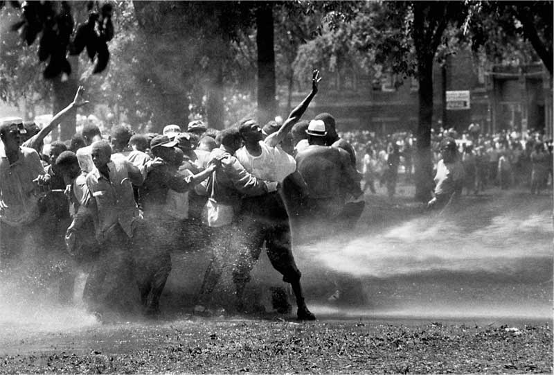 1963. Kelly Ingram Park, Birmingham, Alabama. Békés színesbőrű tüntetők ellen a rendőrség kérésére a tűzoltók vízágyút vetnek be..jpg