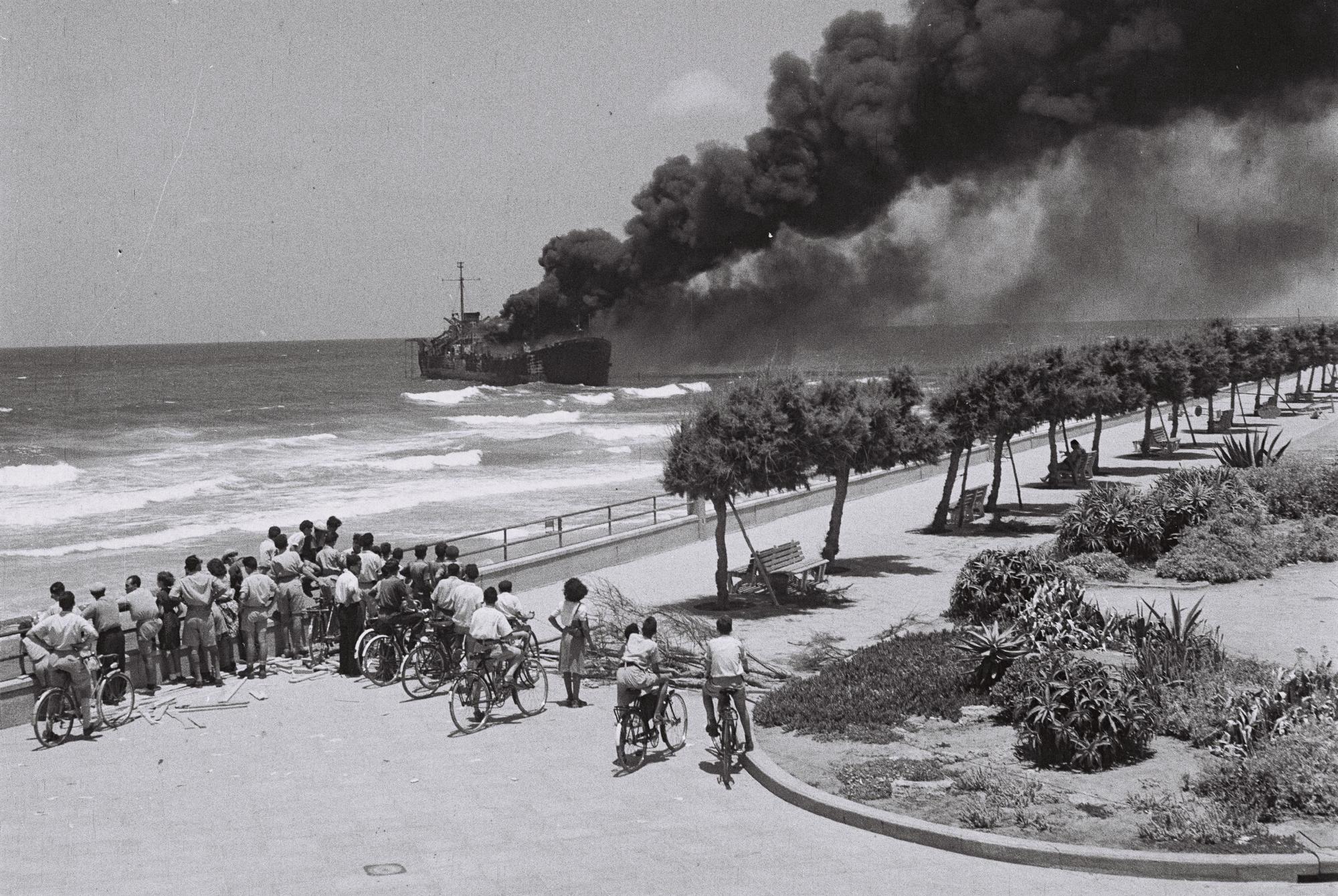 1948. Tel Aviv lakosai nézik az IDF által lebombázott Irgun részére fegyvert szállító teherhajót. A fiatal Izrael legnagyobb belpolitikai nézeteltérése az IDF győzelmével ért véget..jpg